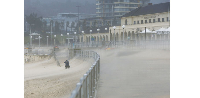  A man takes a picture of Bondi Beachu2019s sand as heavy winds blow it inland.