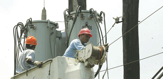 Workers check a power line in Baseco yesterday, a day after several areas in Metro Manila endured rotating brownouts because of the unexpected shutdow