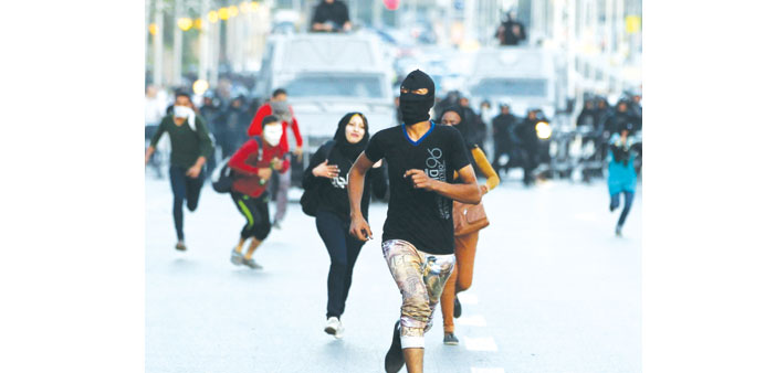 Protesters run from police cars during clashes with security forces after an anti-government protest near the presidential palace in Cairo yesterday.