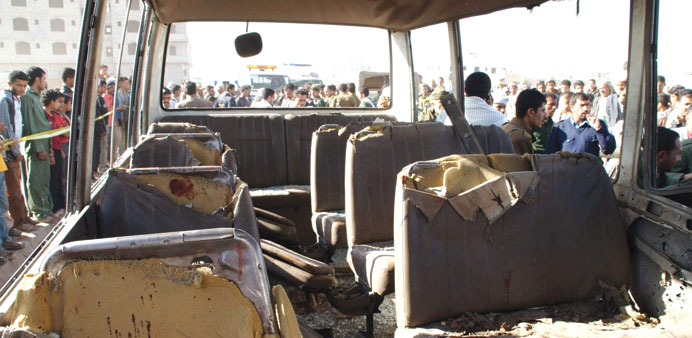 People gather near the damaged military bus after the attack in Sanaa yesterday.