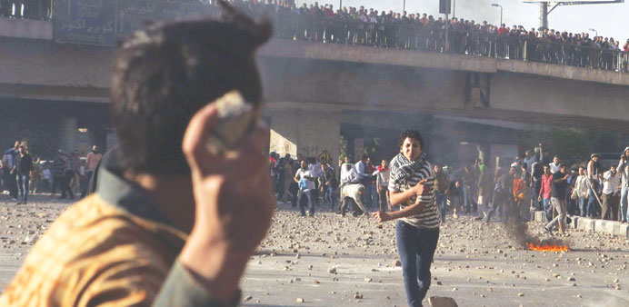 An anti-Mursi protester (centre) is hit by a stone while another throws a stone at Muslim Brotherhood members during clashes in Cairo yesterday.