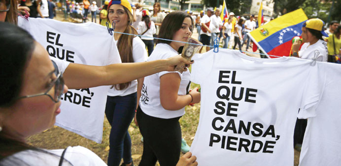 Anti-government protesters buy t-shirts during a march in Caracas yesterday.