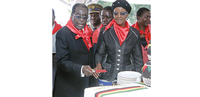 President Robert Mugabe cuts his birthday cake. His wife Grace is beside him.