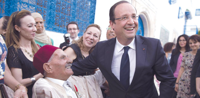 Hollande shares a laugh with a veteran during a visit at the French residency yesterday in La Marsa near Tunis.