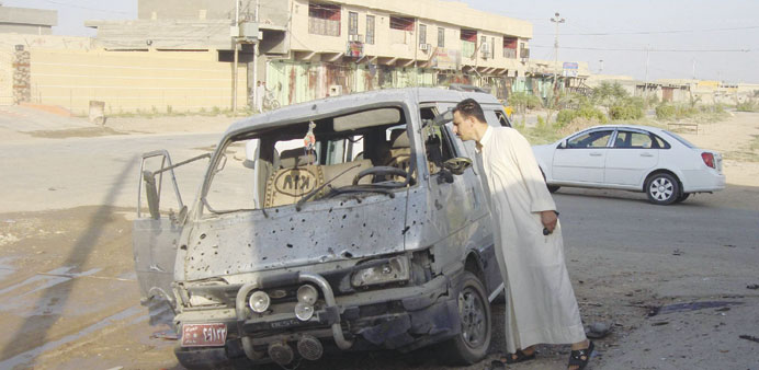 A resident inspects a damaged vehicle a day after a car bomb attack in Dujail, 50km north of Baghdad, yesterday. The attack killed seven people and wo