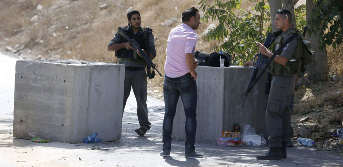 Israeli border guards check the documents of a Palestinian at a roadblock set up on a road close to the Palestinian neighbourhood of Jabal Mukaber in 