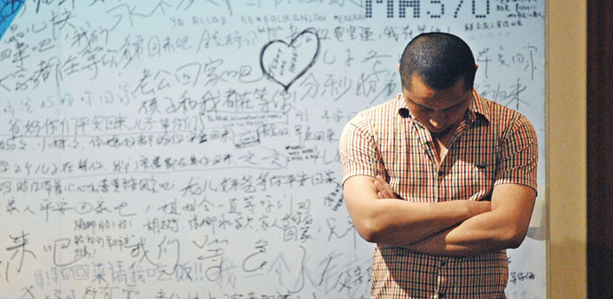 A man stands in front of a billboard in support of missing Malaysia Airlines flight MH370 as Chinese relatives of passengers on the missing aircraft h