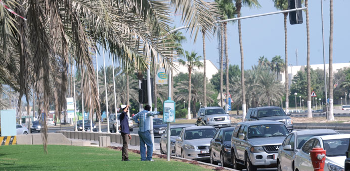 Cars have encroached upon bus stops and commuters now wait on the grass at Al Rumeila Park. Picture: Shemeer Rasheed