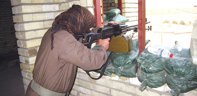 A masked Sunni gunman takes position with his weapon in Fallujah yesterday.