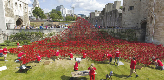 Volunteers install porcelain poppies as part of the art installation u2018Blood Swept Lands and Seas of Redu2019 by ceramic artist Paul Cummins and theatre st