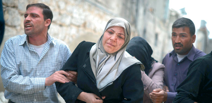 Men help a woman who was wounded in shelling by government forces in Aleppo yesterday.