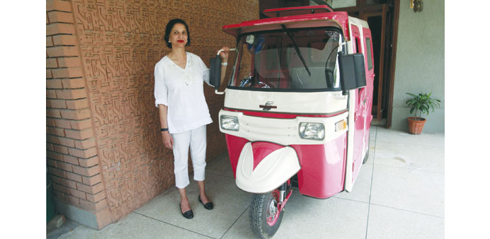 Zar Aslam, president of Pakistanu2019s non-profit Environment Protection Fund, standing next to a pink rickshaw.