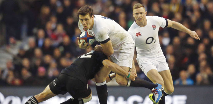 New Zealandu2019s Aaron Cruden (L) tackles Englandu2019s centre Joel Tomkins (C) during the international rugby union test match at Twickenham Stadium in Lond