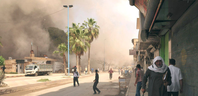 People run for cover after what activists said was shelling by regime forces in Raqqa province, eastern Syria, on Friday.
