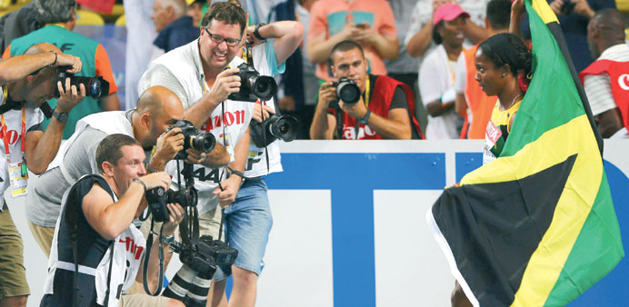 Shelly-Ann Fraser-Pryce (right) poses for the photographers after winning 100m final in Moscow yesterday. (Reuters)