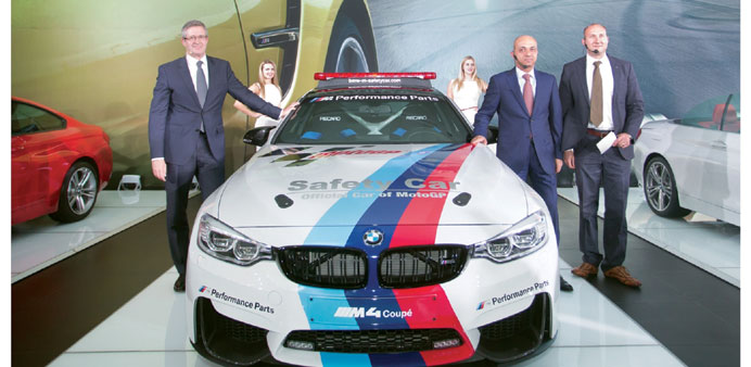 Officials stand next to the all-new BMW M4 Coupu00e9, the official safety car for the 2014 MotoGP.