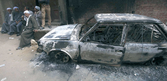 People are seen near a burnt car after the clashes in Al Khusus yesterday.