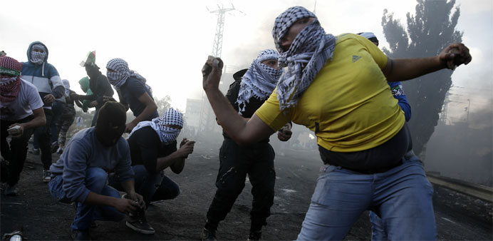 Palestinian protesters throw stones during clashes with Israeli security forces