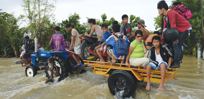 Residents ride on a farm tractor with their belongings including motorcycles as they cross floodwaters over a national highway due to heavy rains brou