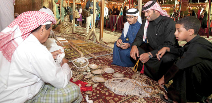 Visitors to the Qatar booth watch traditional craftsmen at work.