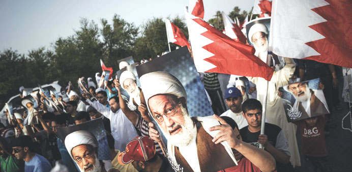 Demonstrators hold pictures of Sheikh Isa Qassim during a protest in the village of Abu Saiba, west of Manama, yesterday.