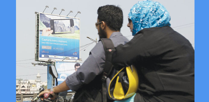 Commuters ride past a billboard featuring a credit card advertisement in Mumbai.