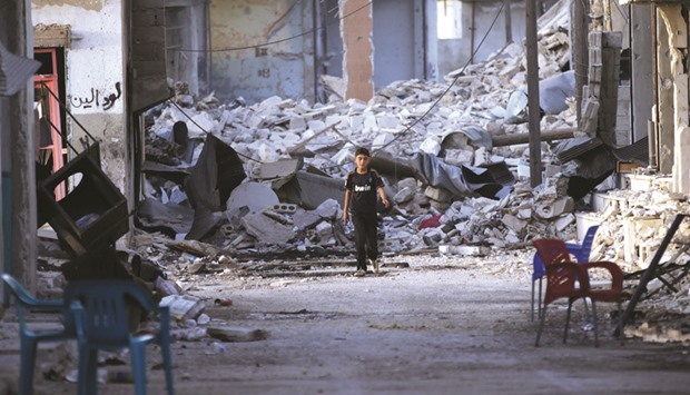 A boy walks past damaged buildings in the northern Syrian rebel-held town of Al-Waqf, in Aleppo Governorate, yesterday.