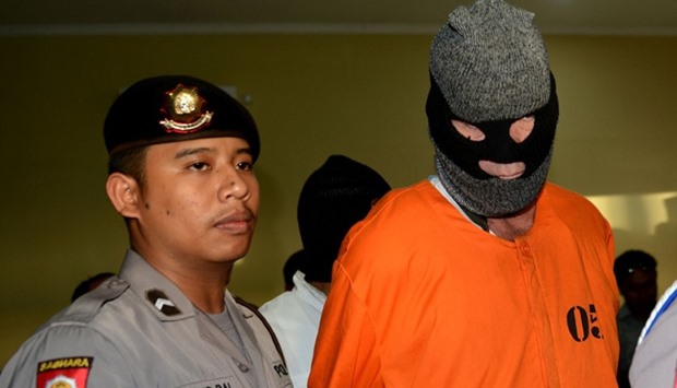 David Fox is escorted by police after a press conference at a police station in Denpasar on Bali Island.