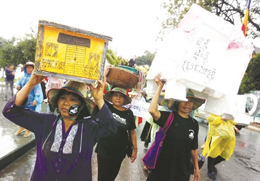 People hold up models of houses as they take part in a rally marking World Habitat Day, to appeal to the Cambodian government to stop evicting people from their homes, according to rally organisers, in central Phnom Penh yesterday.