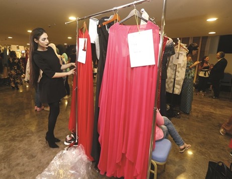Emirati model Rafeea al-Hajsi looks at dresses by Lebanese designer Aiisha Ramadan prior to the walking down the catwalk in Ramadanu2019s show at the Arab Fashion Week in Dubai on Sunday.