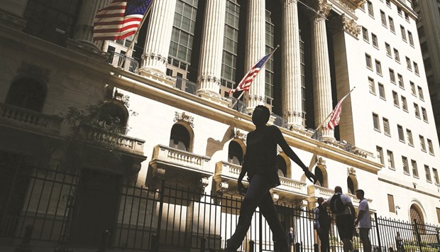 People walk by the New York Stock Exchange. While analysts predict net income for S&P 500 Index members fell 1.6% in the July-September period, the expected rate of decline is so small that it will almost certainly evolve into a gain when companies are done beating estimates.