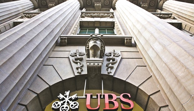 A sign hangs above the entrance to UBS headquarters in Zurich. Starting next month, the Swiss bank will give some UK customers with as little as u00a315,000, or about $18,000, access to an online service that invests their money based on information they provide about themselves.