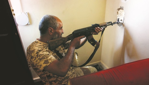 A fighter from Libyan forces allied with the UN-backed government aims his weapon through a hole in a wall as he looks for Islamic State militants in their remaining holdouts in Sirte yesterday.