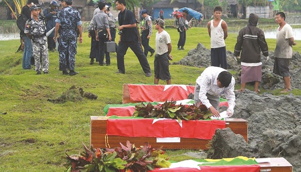 Myanmar border police prepare flag draped coffins bearing nine bodies of border guards killed in mysterious raids during a funeral ceremony at a cemetery in Maungdaw in Rakhine State on October 11, 2016.Fear gripped Myanmaru2019s Rakhine state on October 11 as troops hunted attackers behind recent deadly raids, which activists warned are being used as a cover to crackdown on the persecuted Rohingya minority.
