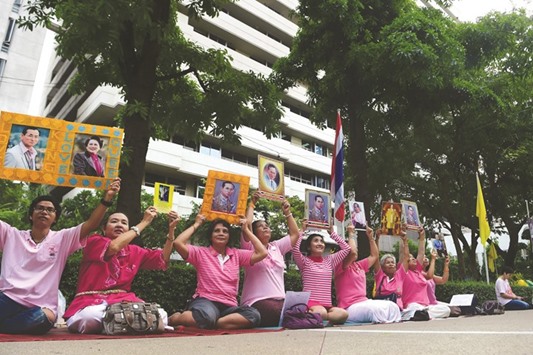 Women hold portraits of Thai King Bhumibol Adulyadej as they pray for his health at Siriraj Hospital, where the king is being treated, in Bangkok yesterday.