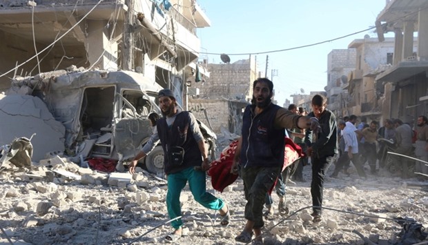 Syrian volunteers carry an injured person on a stretcher following Syrian government forces airstrikes on the rebel held neighbourhood of Heluk in Aleppo, on September 30, 2016