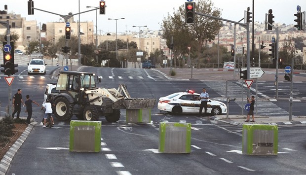 Israeli policemen stand guard as cement blocks are placed by Israeli security forces on a road linking the Arab east Jerusalem neighbourhood of Beit Hanina and West Jerusalem, yesterday, ahead of Jewish holiday.