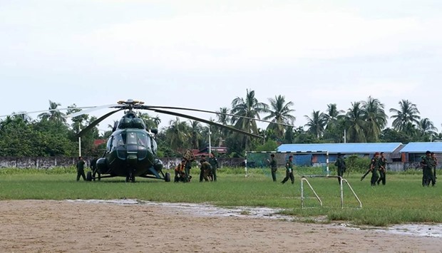 Myanmar military troops walk by a helicopter that took them to Maungdaw located in Rakhine State