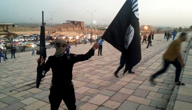 A fighter of the Islamic State holds the IS flag and a weapon on a street in the city of Mosul, Iraq June 23, 2014