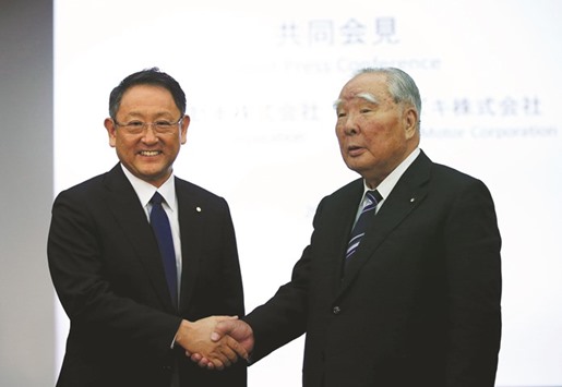 Toyota Motor president Akio Toyoda (left) shakes hands with Suzuki Motor chairman and CEO Osamu Suzuki at their joint news conference in Tokyo yesterday. Both companies said that they had just begun discussing possible cooperation citing technological challenges and the need to keep up with consolidation in the global auto industry.