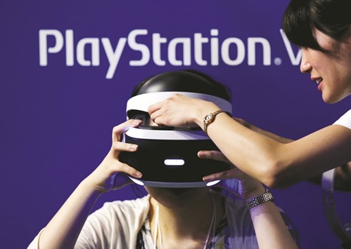 A hostess helps a woman to wear Sonyu2019s PlayStation VR headset at Tokyo Game Show 2016 in Chiba. The electronics giant is set to launch its new virtual reality headset, joining Facebook, Samsung and Google in a market that analysts say could boost the global gaming sector.