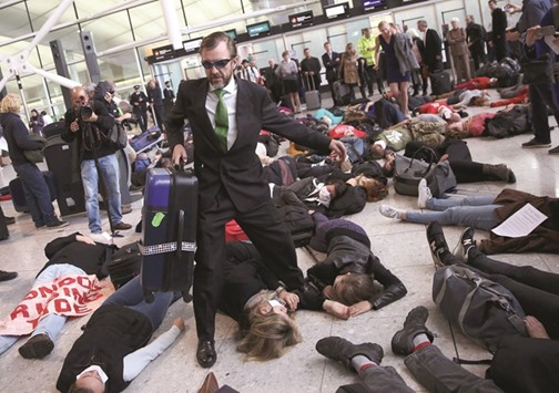 Climate activist group Reclaim the Power lie on the ground and carry luggage during a protest against airport expansion plans.