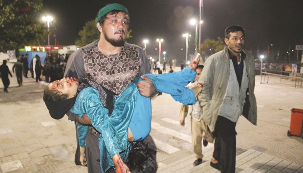 An Afghan man carrying a wounded girl after an attack by gunmen at the Karte Sakhi shrine in Kabul.
