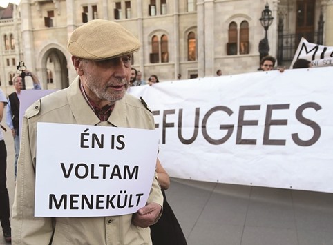 An elderly man walks with his placard reading u2018I was refugee alsou2019 in front of activists holding up a banner reading u2018Refugees welcomeu2019 during protests on Friday near parliament in Budapest against the migration policy of the Orban government.