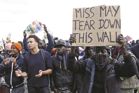A migrant holds a placard with a message for Britainu2019s prime minister as they face off with French riot police during a protest near the u2018Jungleu2019 in Calais.