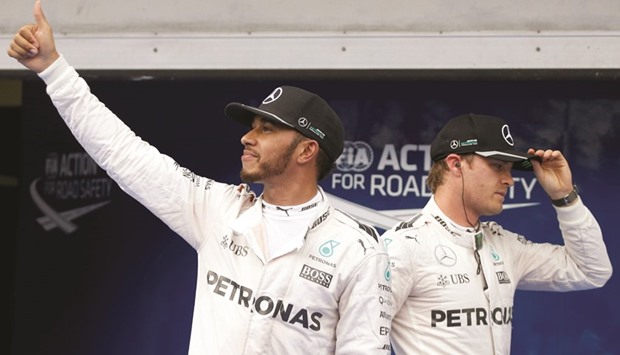 Mercedes driver Lewis Hamilton (left) of Britain celebrates his pole position as his teammate Nico Rosberg of Germany walks by after the qualifying session for the Malaysia Grand Prix in Sepang, Malaysia. (Reuters)