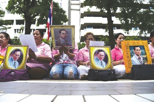 Women hold portraits of Thai King Bhumibol Adulyadej as they pray for his health at Siriraj Hospital, where the king is being treated, in Bangkok.