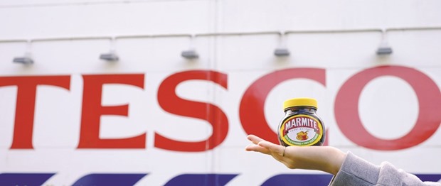 A woman holds a jar of Marmite, a Unilever brand, outside a Tesco store near Manchester. The biggest British retaileru2019s stocks were 3% down at the close yesterday.