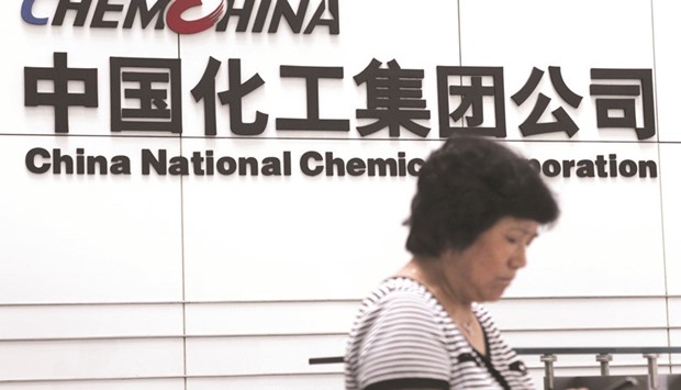 A woman checks her phone at the headquarters of China National Chemical Corporation in Beijing. If approved, Chinese state-owned chemical companies Sinochem and ChemChina merger would be among the largest between two state-owned enterprises in the country, sources said yesterday.