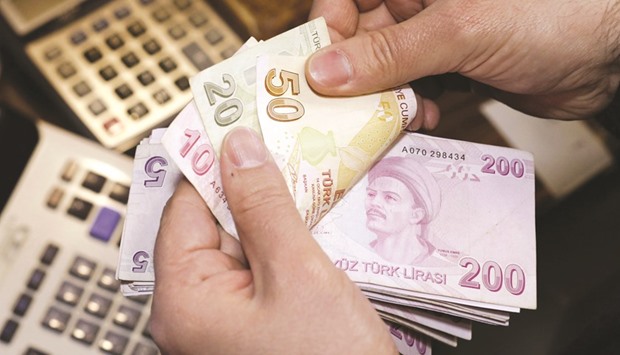 A money changer counts Turkish lira bills at a currency exchange office in Istanbul. Moodyu2019s downgraded the nationu2019s credit rating to junk in September, citing a slowdown in the economic growth and risks to its ability to attract foreign capital following the attempt to overthrow the government.